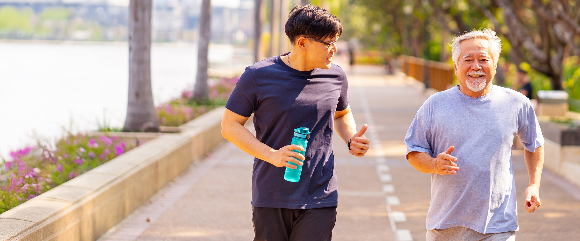 Older man and younger son, jogging on a boardwalk.