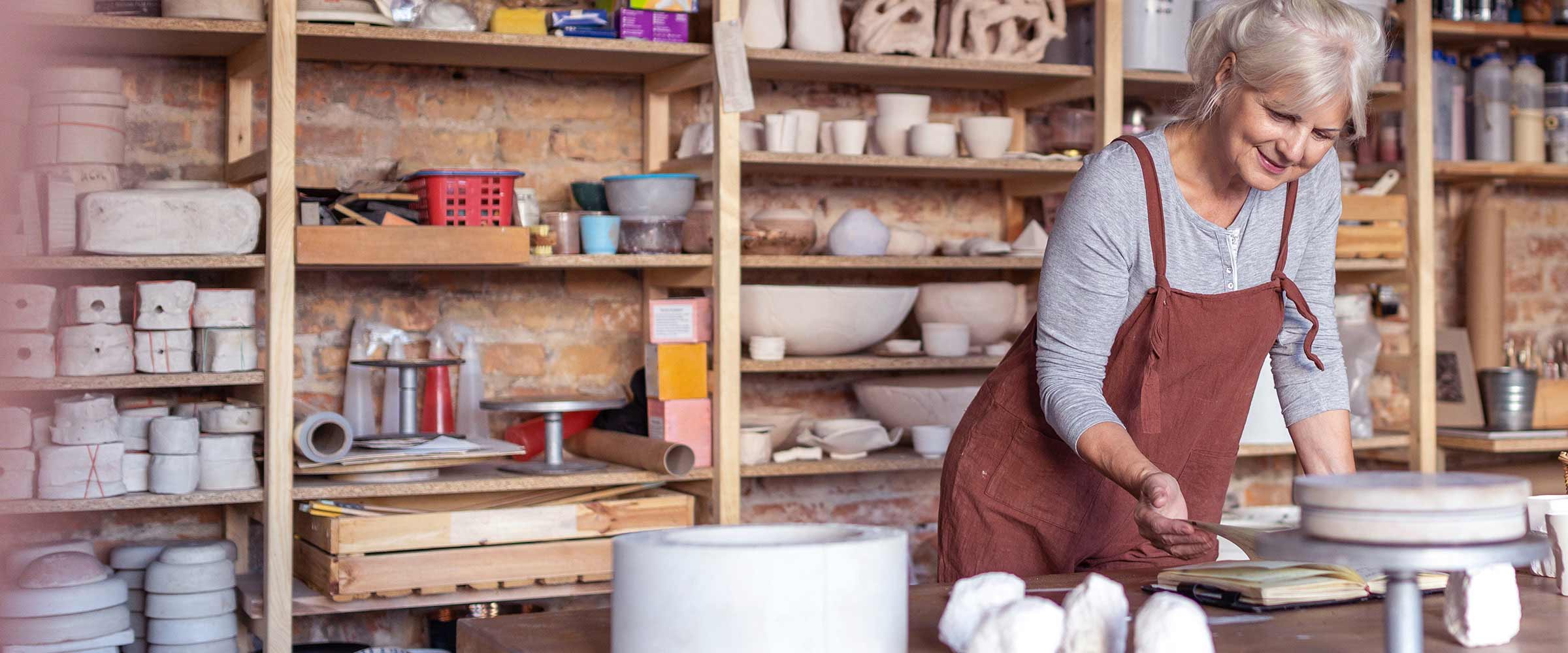Photo of older woman working at a pottery making shop.