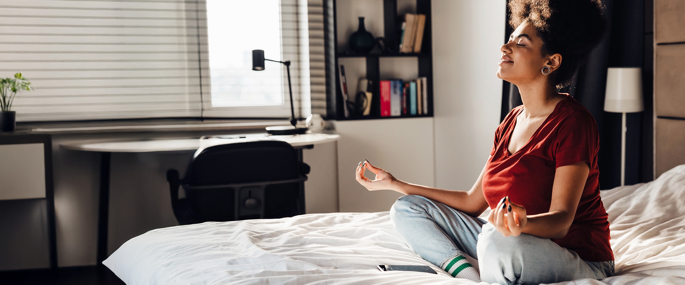 Photo of woman on bed, legs crossed, meditating.