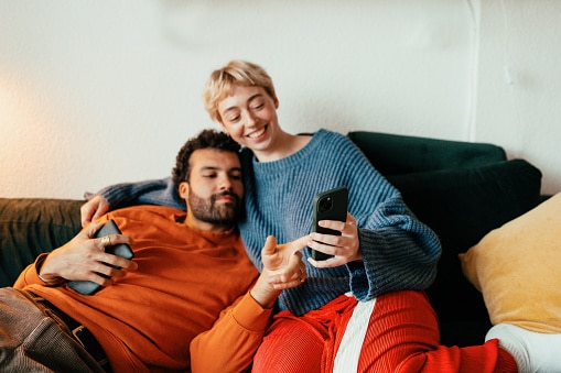 Couple relaxing together on couch browsing on phone