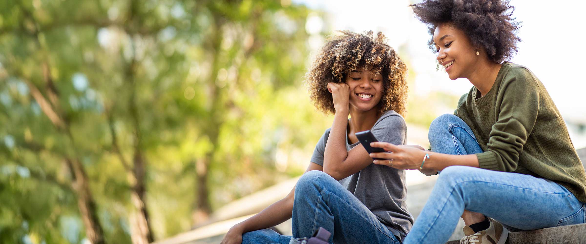 Two synchrony customers looking at a mobile device outdoors. 