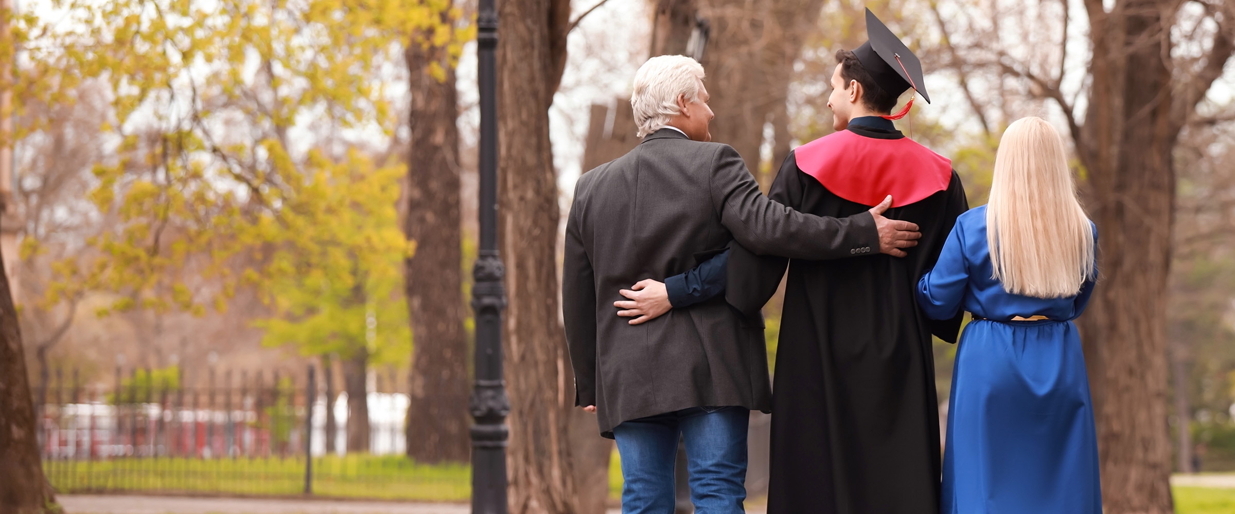 Photo of teen in graduation gown with parents alongside them.