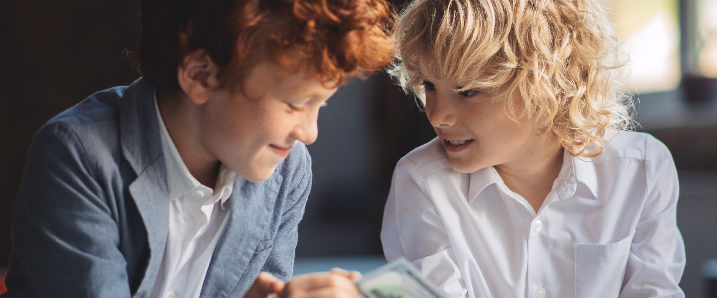 Photo of two kids looking over a few dollar bills.
