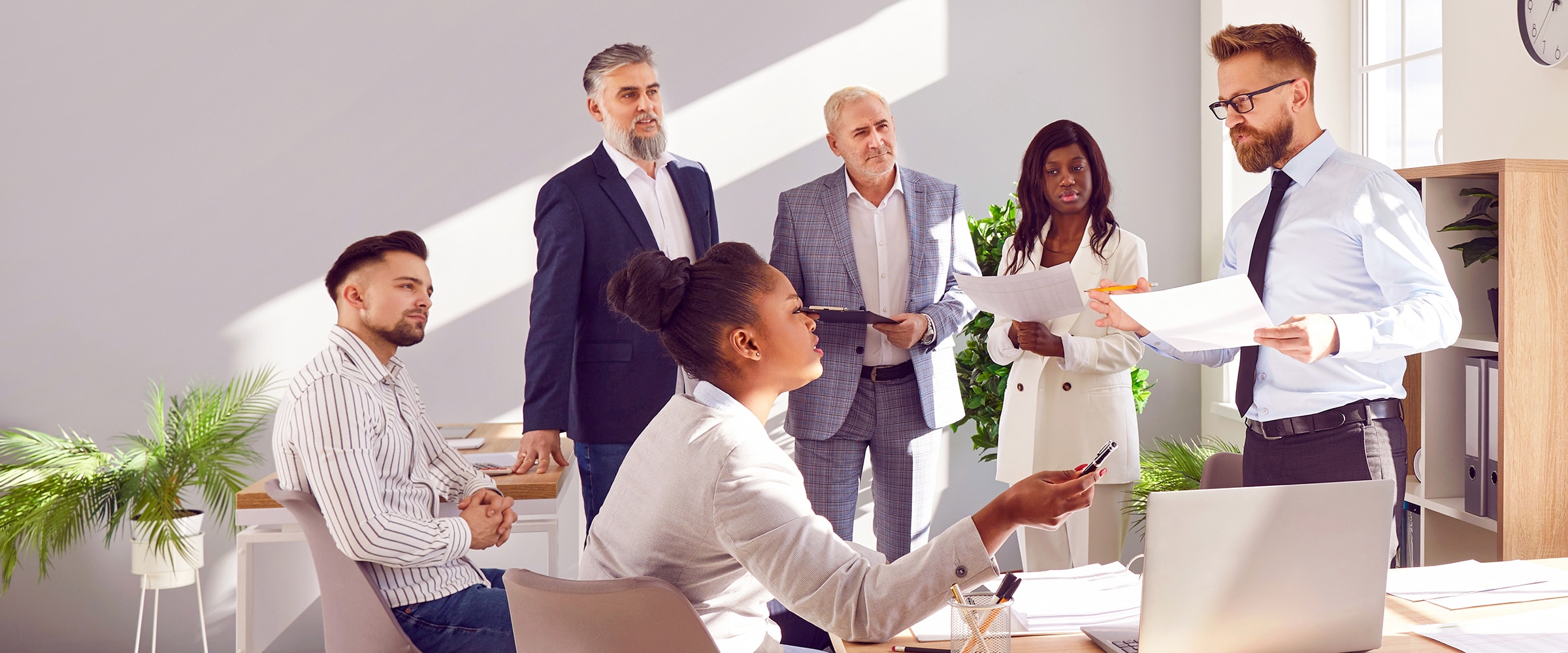 Photo of employees around a table in an office setting.