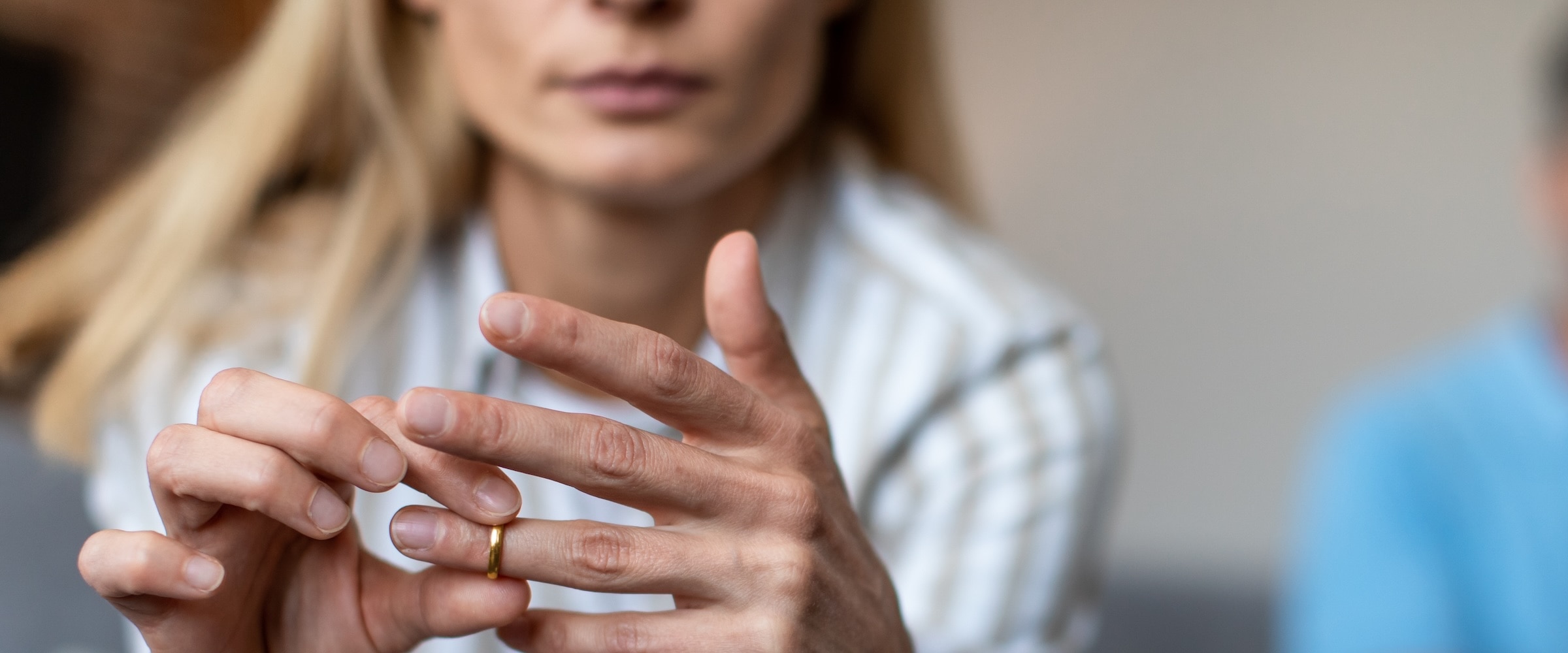Photo of woman sliding wedding ring on her finger.