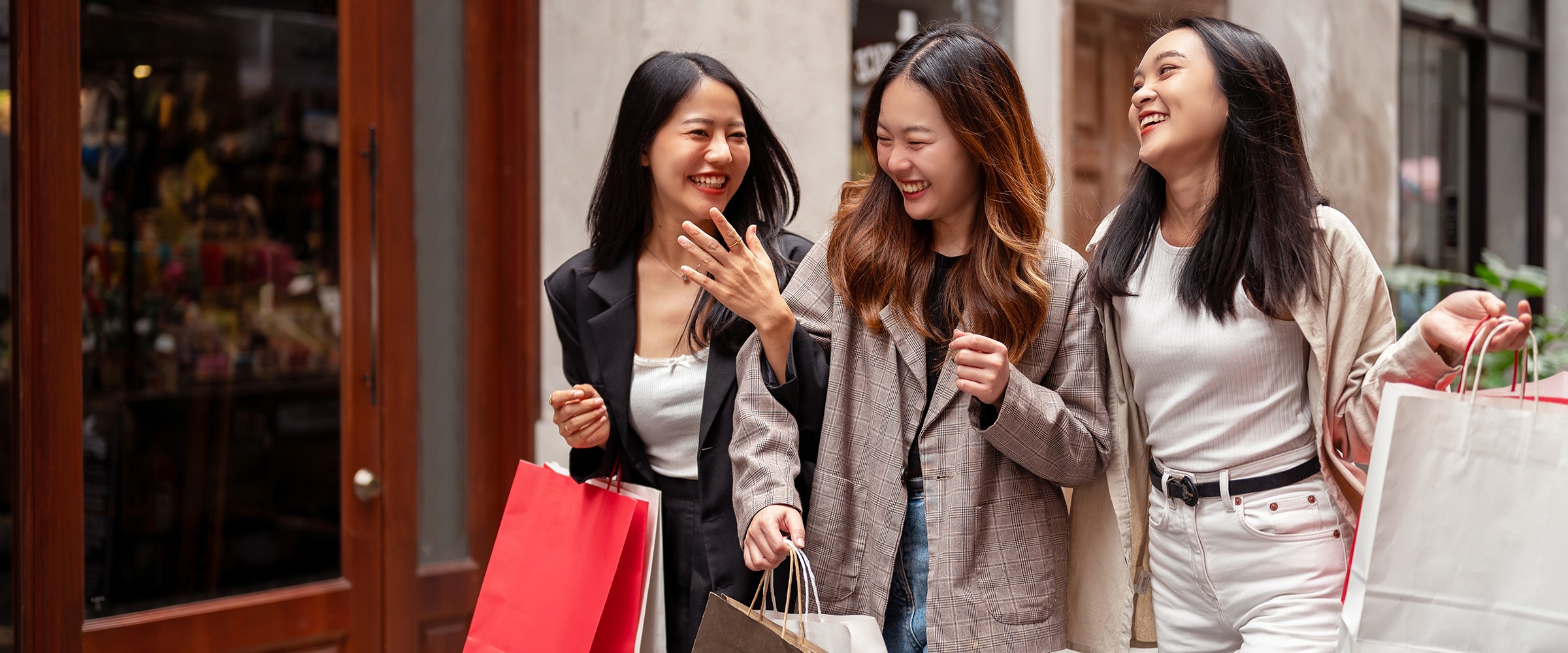 Photo of young women walking down street holding shopping bags.