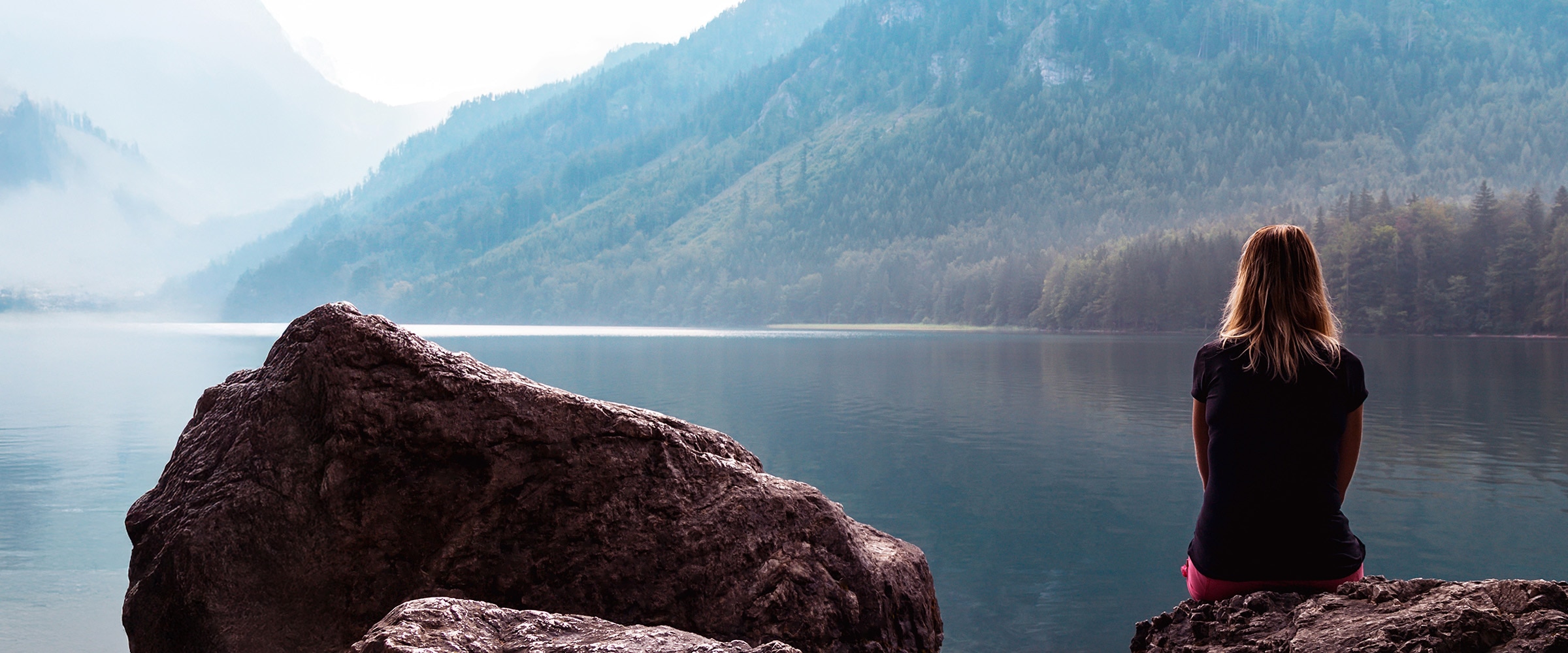 Photo of woman sitting at lake's edge.