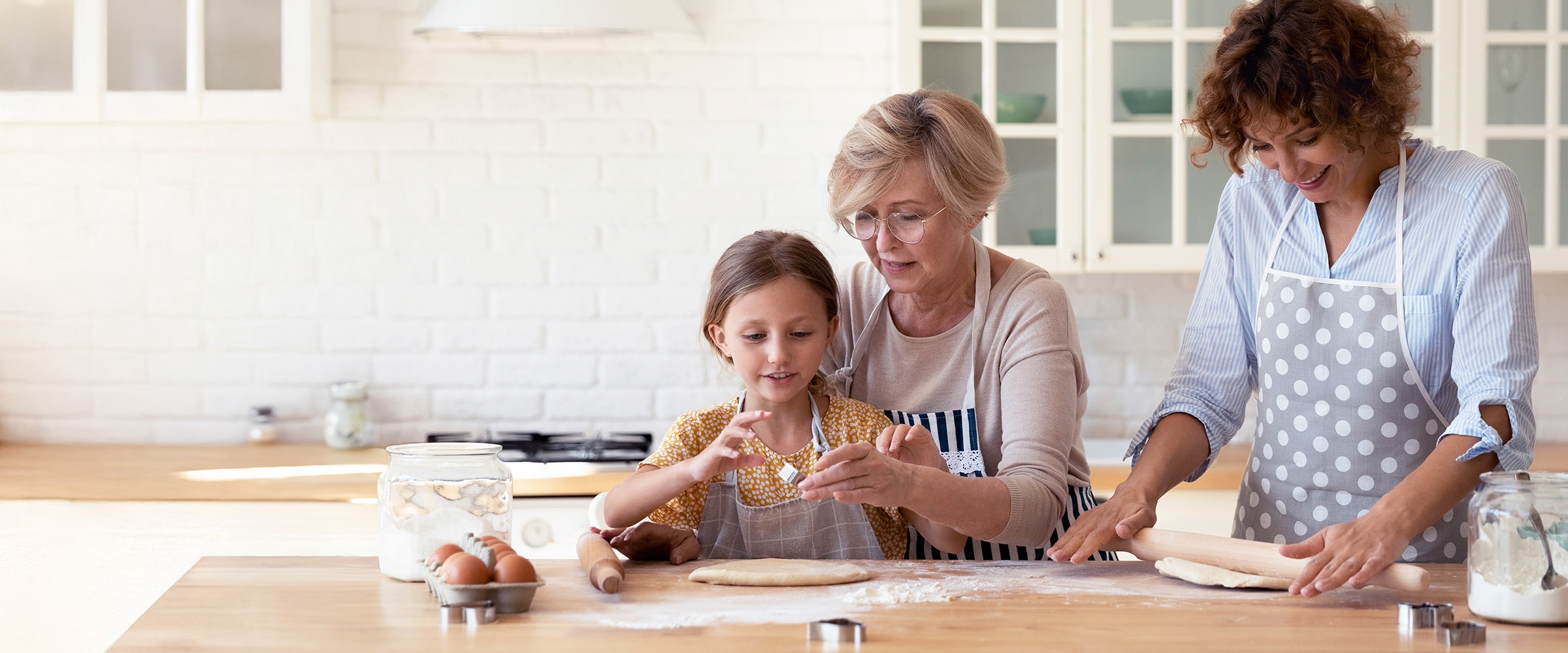 Photo of mother and daughter making a cake along side an older woman.