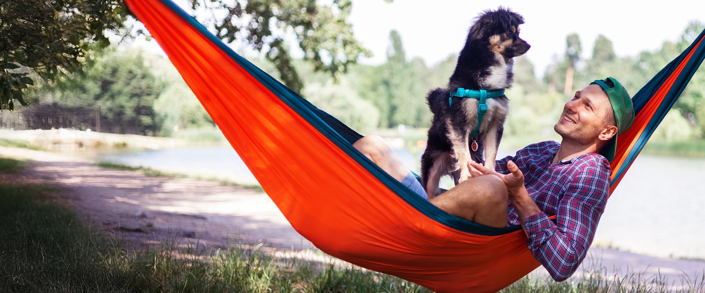 Photo of man resting in a hammock with his dog.