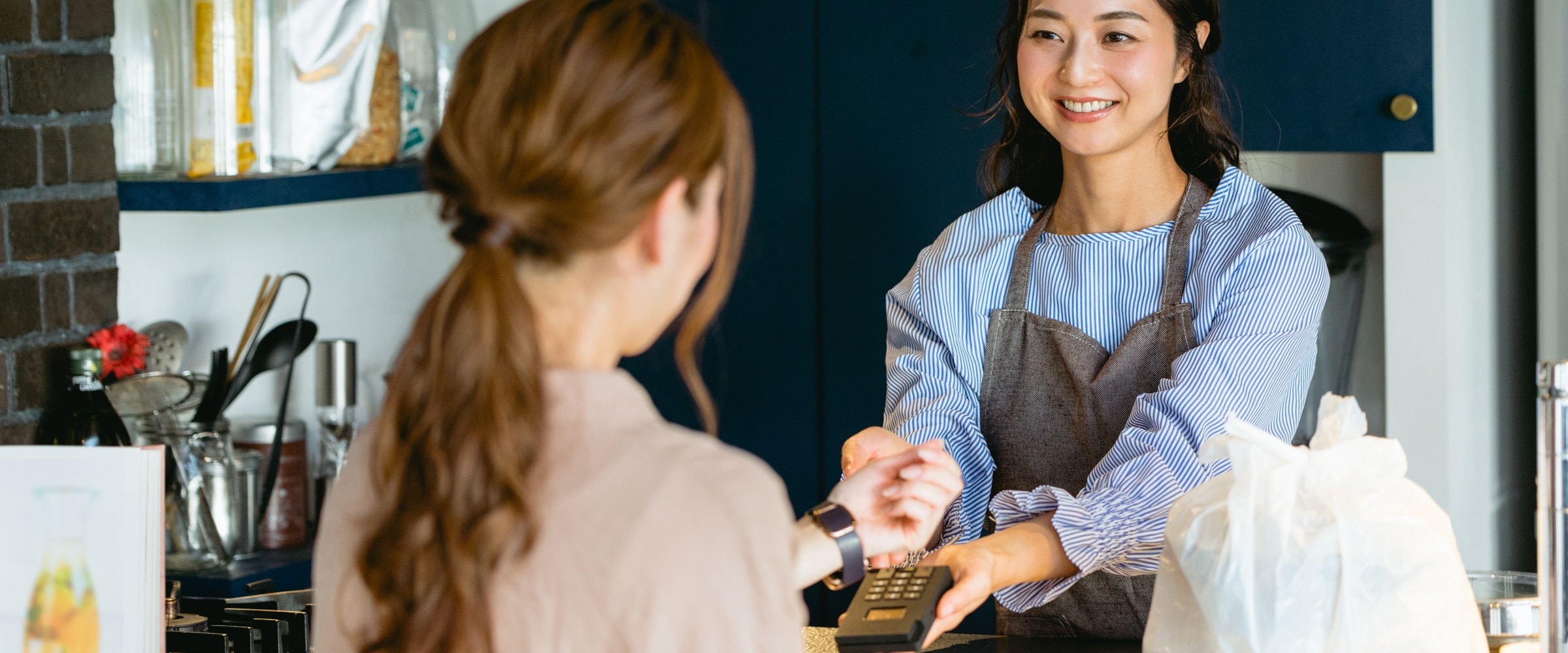 Photo of young woman working as a store clerk helping a customer.