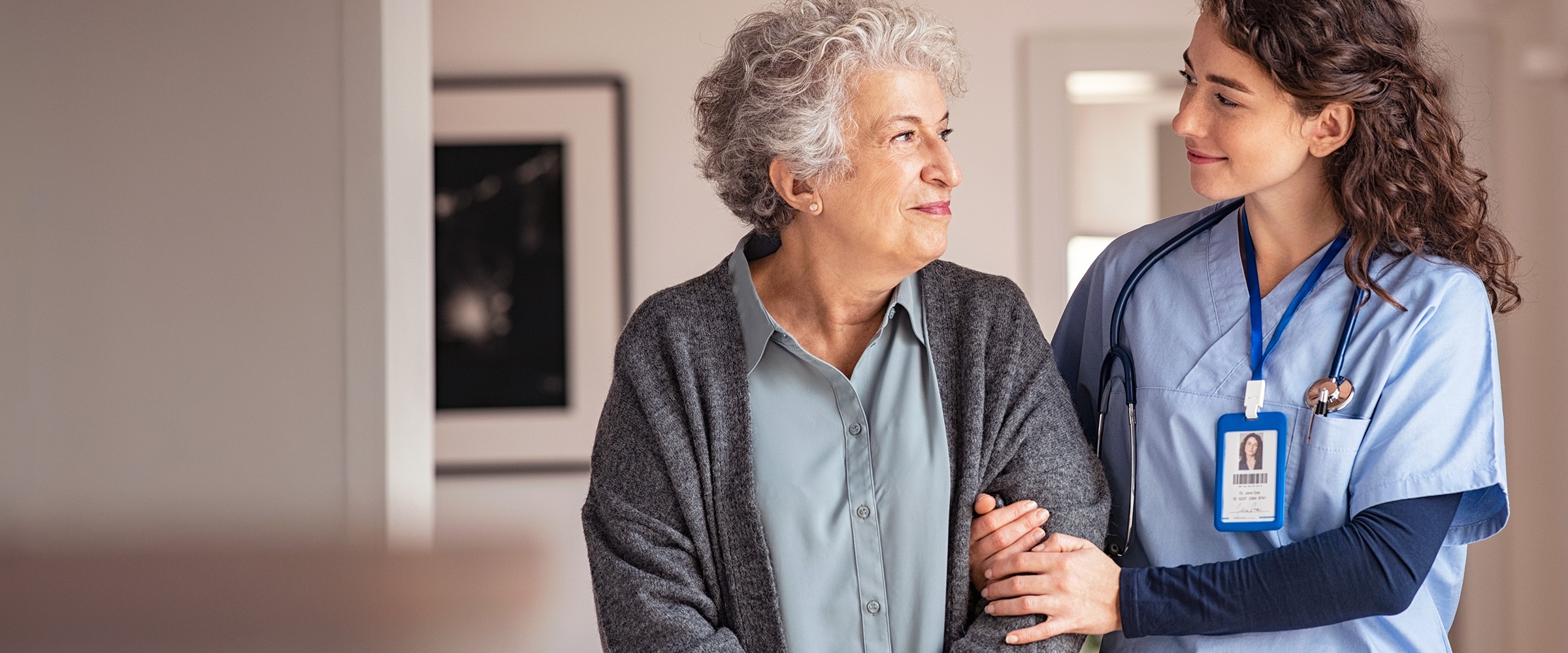 Photo of nurse walking arm-in-arm with older woman.