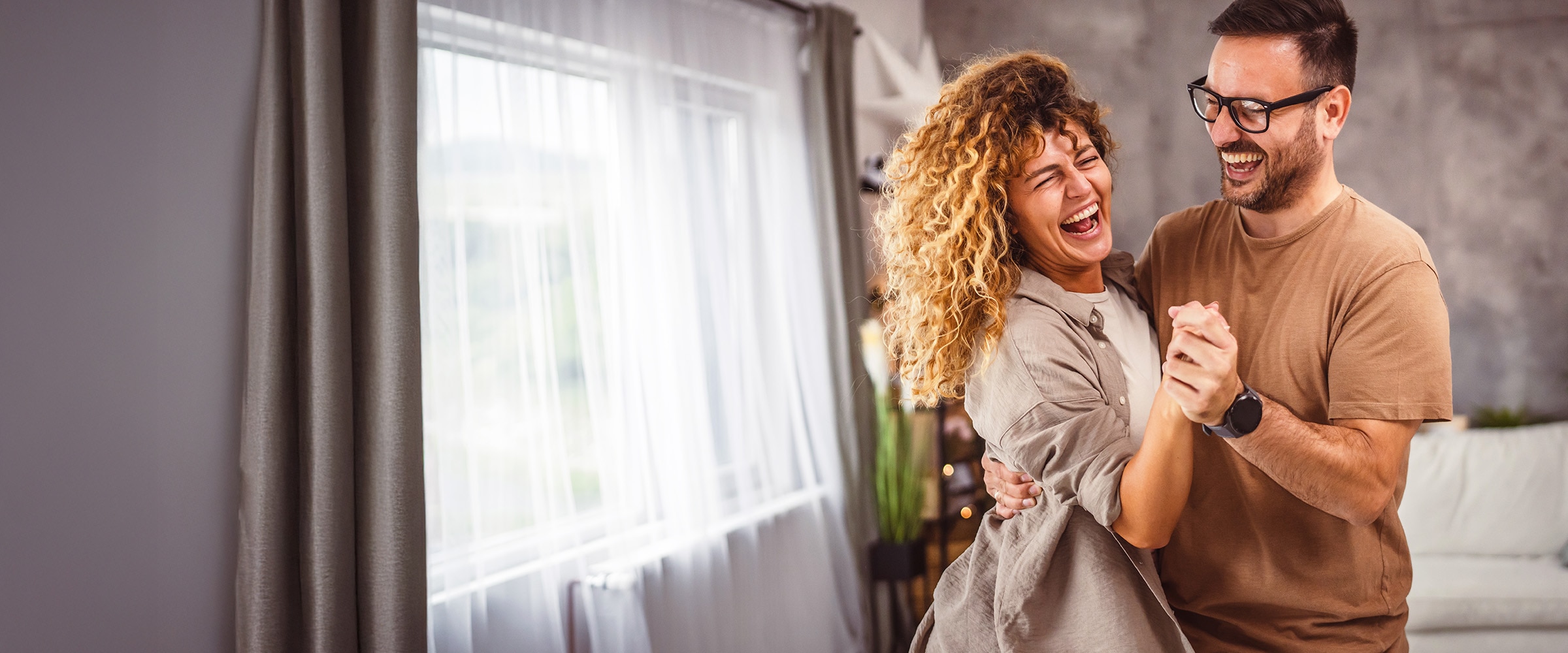 Photo of couple laughing together inside home.
