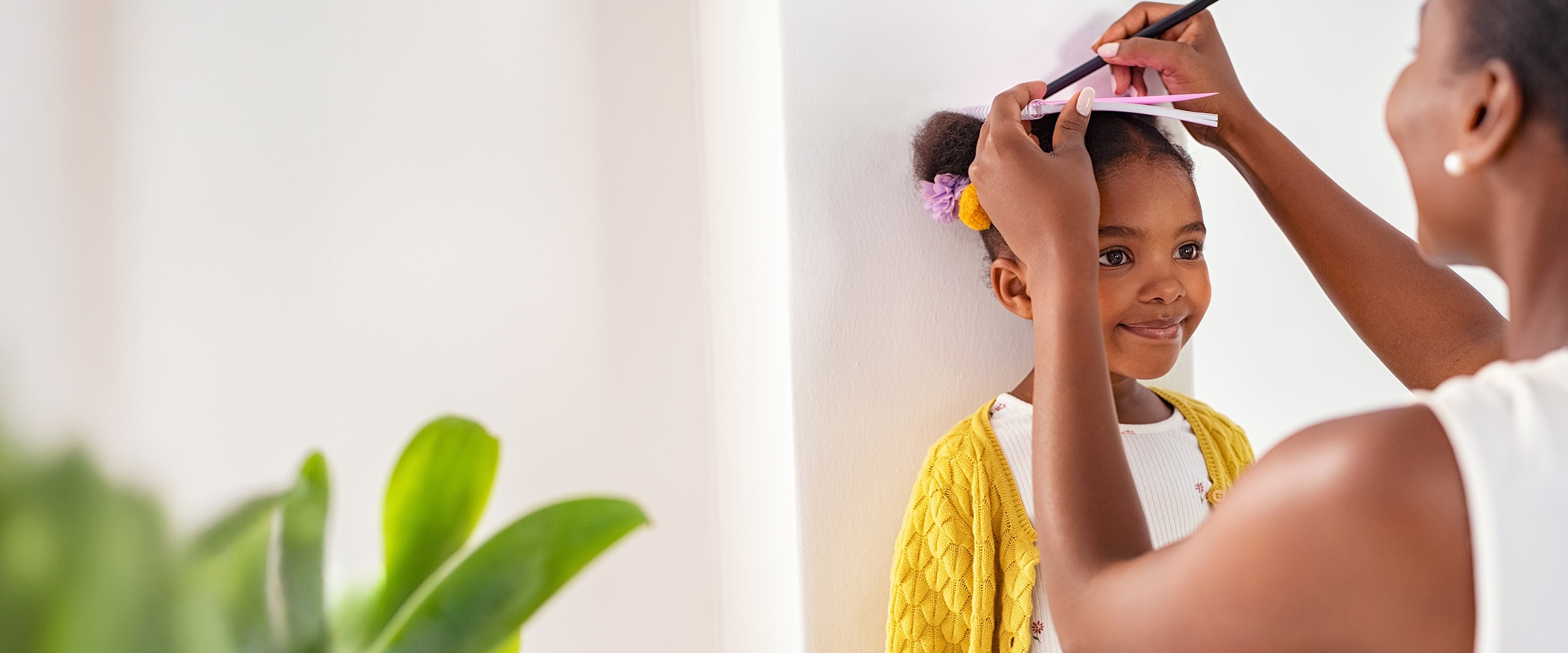 Photo of mom measuring her daughter's height up against a wall.