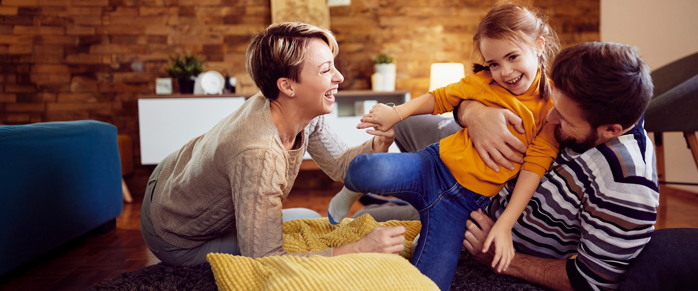 Pnoto of couple and child being playful in living room.