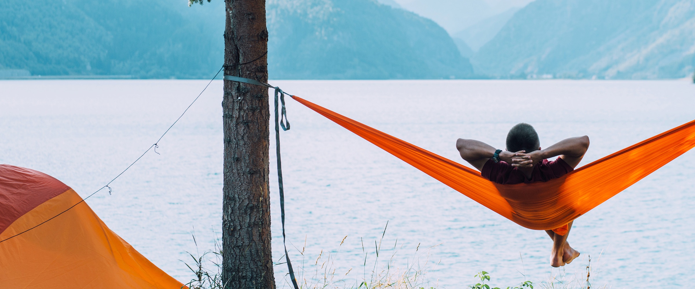 Photo of woman relaxing in a bright orange hammock.