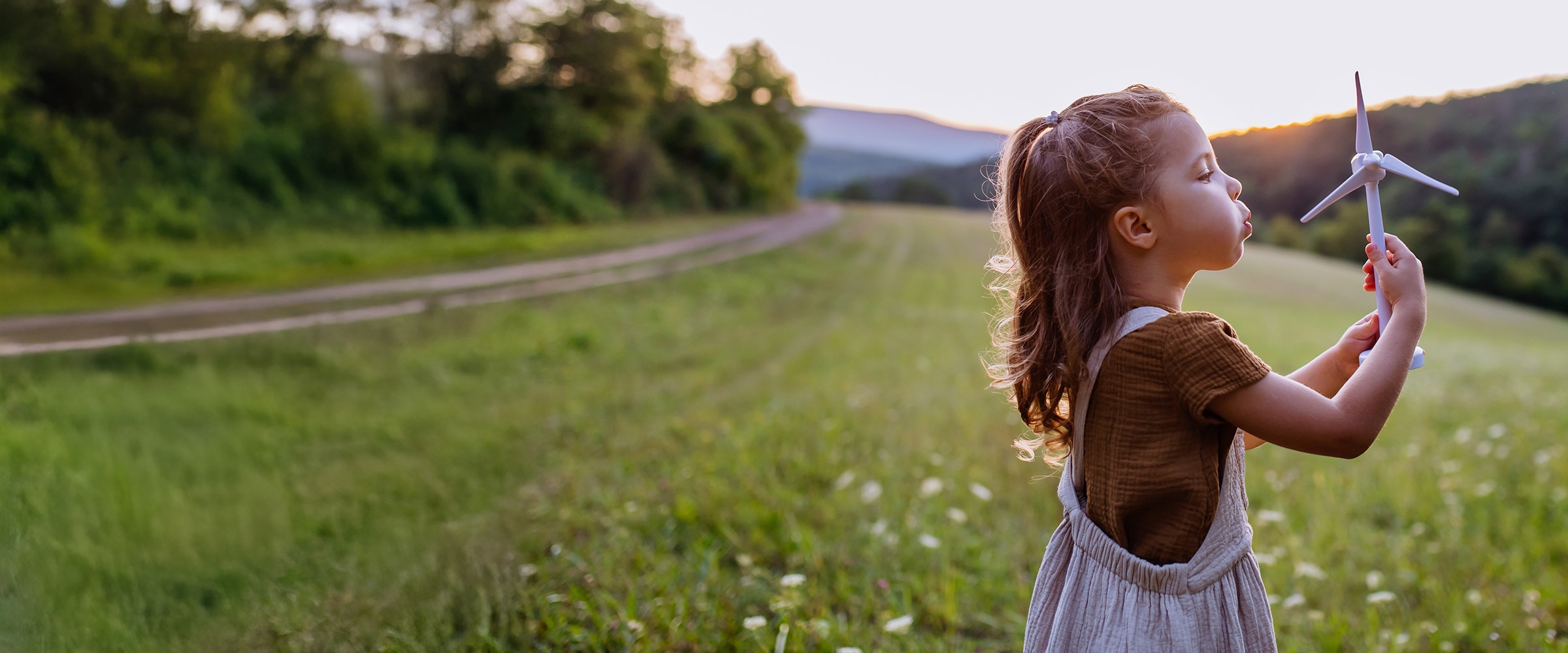Photo of young girl blowing on a hand held windmill.