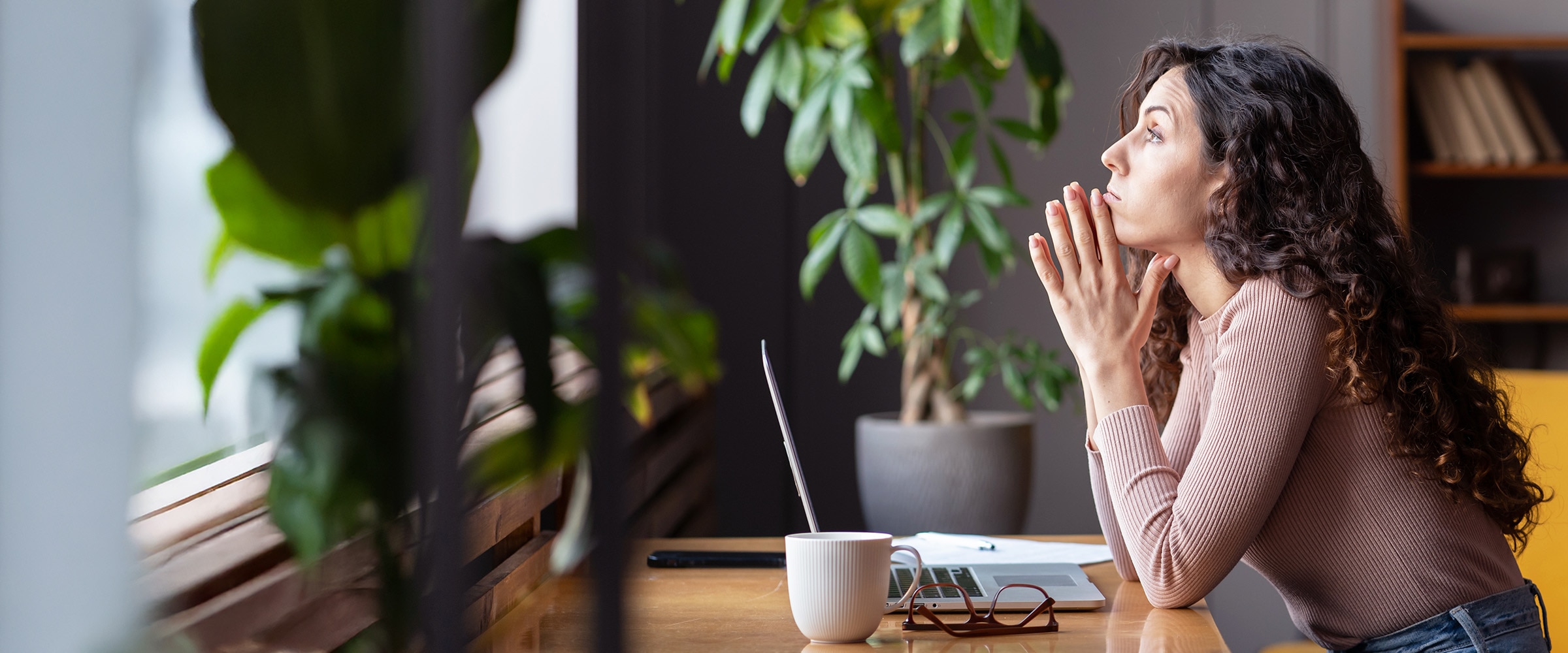 Photo of young woman pondering while sitting at a work desk.