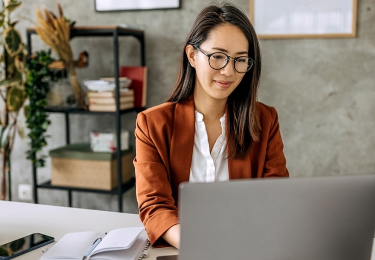 Woman sitting at desk working on her laptop.