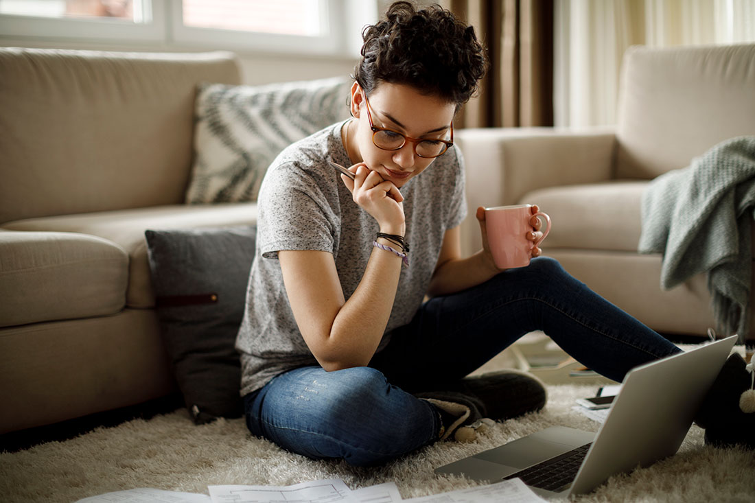 Store associate sitting on floor with coffee and laptop.