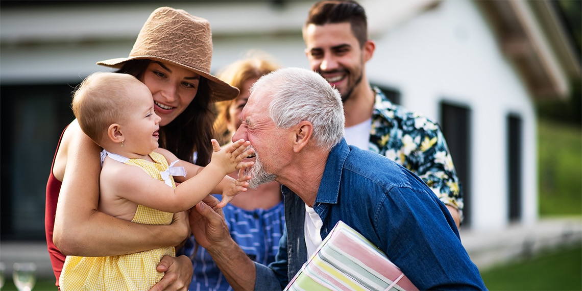 Photo of different generations of a family together in front of a home.